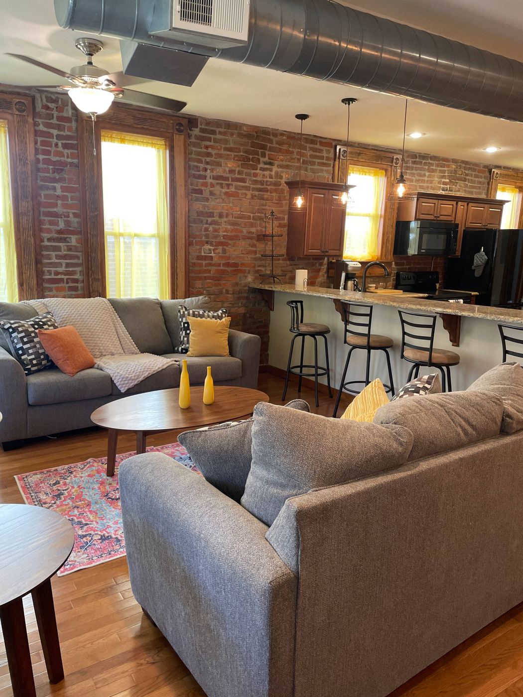 Living room and kitchen at Chateau Du Burg with exposed brick walls, tall windows, and a breakfast bar